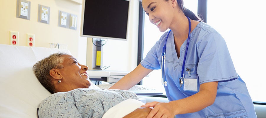 nurse holding hand of patient in bed