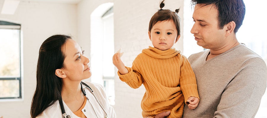 A doctor in a Medicaid clinic speaks to a father with his child
