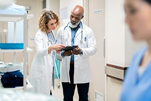 Coronavirus COVID-19 Information for Patients and Communities stock. Two clinicians reviewing a patient chart.