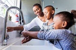 Coronavirus COVID-19 Supplies and Personal Protection Equipment (PPE) stock. A mother and her son and daughter washing their hands.