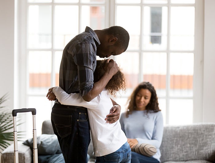 Father and daughter hugging with mother sitting on couch