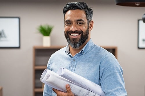 man holding plans in left hand smiling into camera