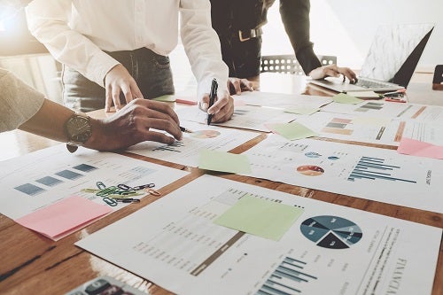 three people at table reviewing charts and graphics with numbers