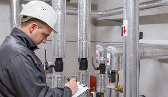 a man writing on a clipboard in a maintenance room