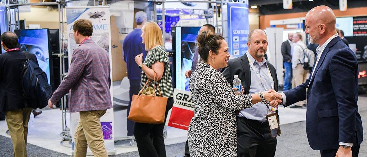 Attendees shaking hands in the exhibit hall