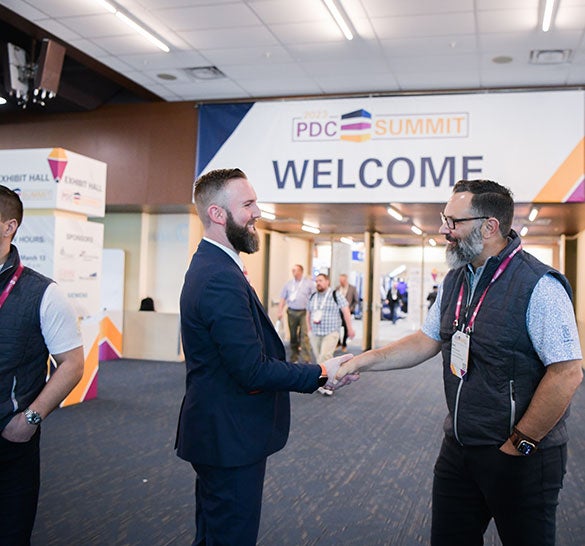 PDC Summit attendees shake hands in the exhibit hall