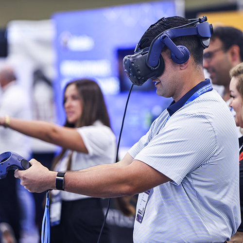 man standing wearing VR goggles and holding controller in hands in front of him